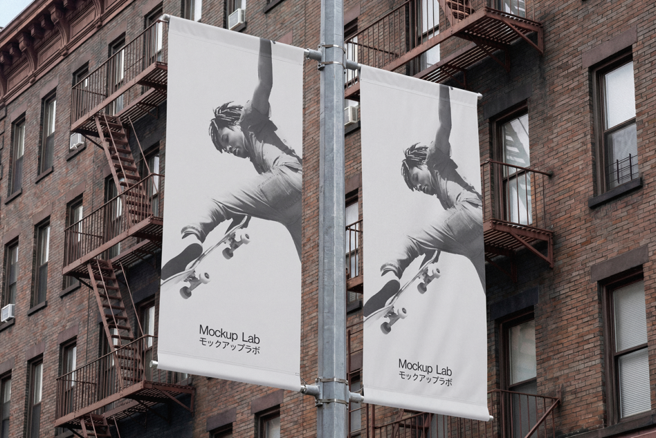 Two white street banners on brick facade with skateboard imagery in black ink