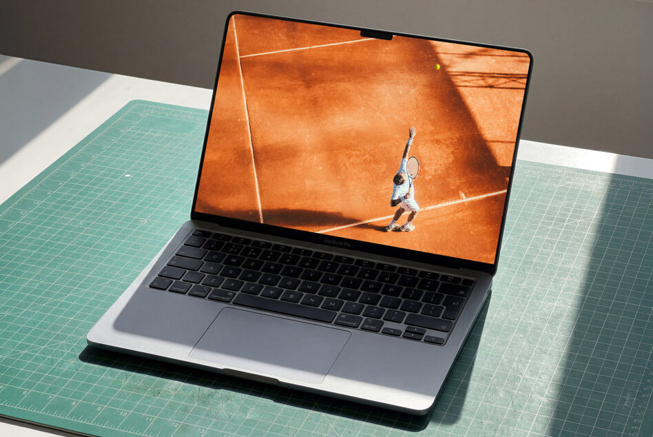 MacBook displaying tennis player image, sitting on grid mat workspace