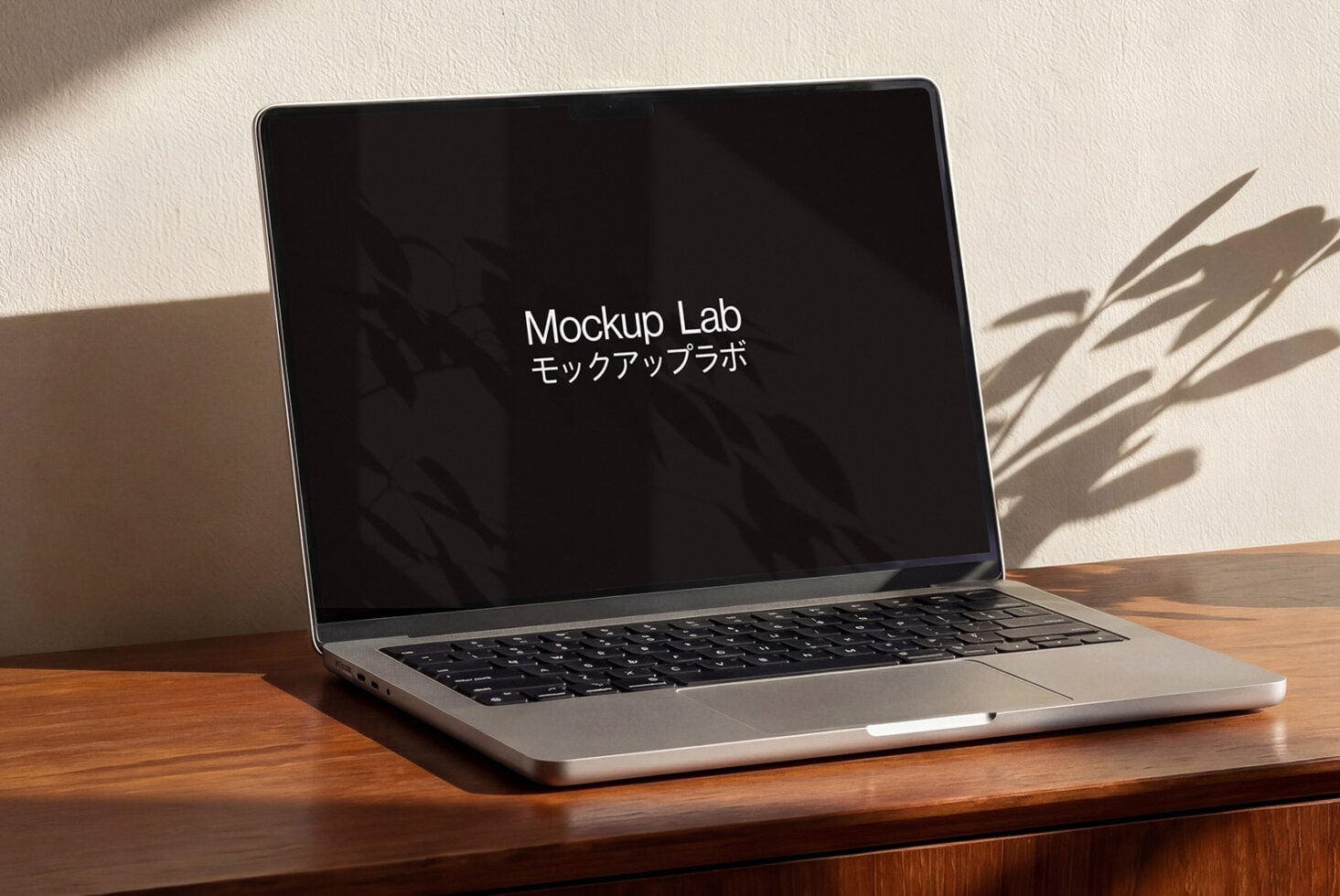 MacBook on wooden table with black screen, natural window light casting shadows