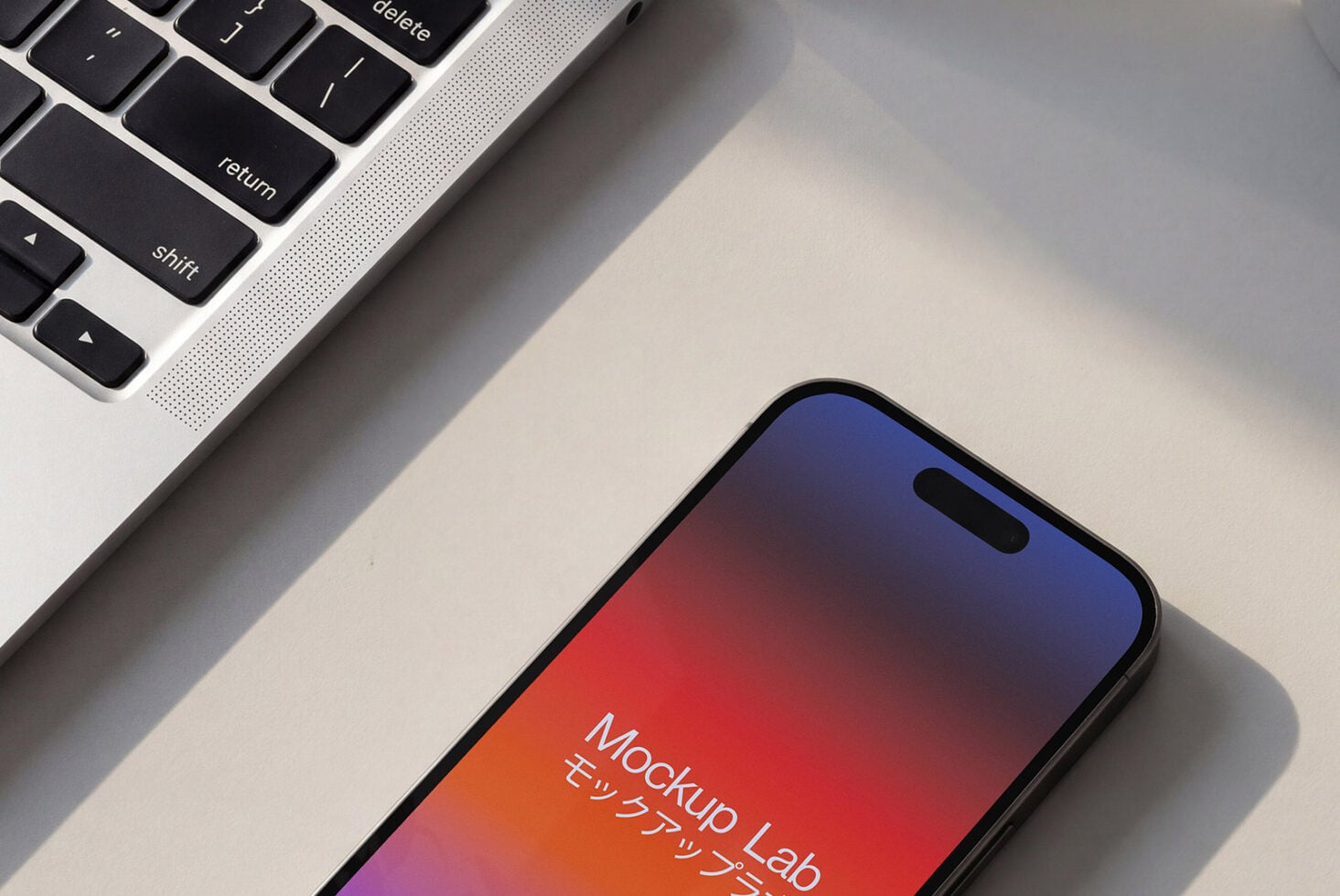 Flatlay of phone beside laptop showing vibrant red to blue gradient display