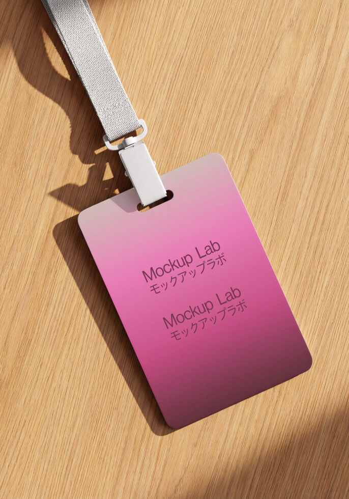 Gradient pink badge with gray lanyard lying flat on wood table