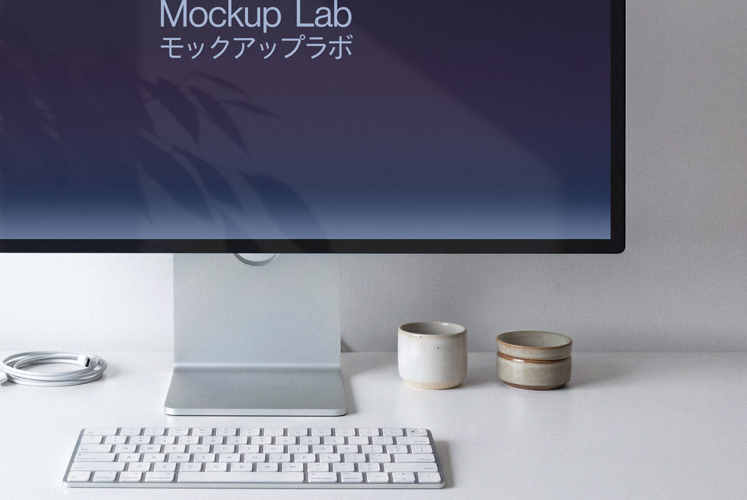 Desktop monitor showing purple gradient with Japanese characters, ceramic cups, white keyboard