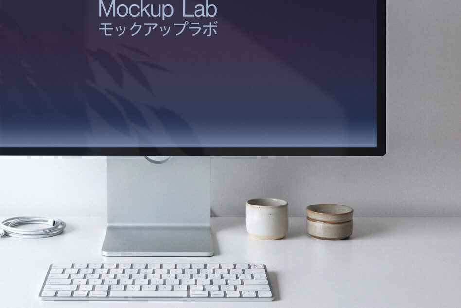 Desktop monitor showing purple gradient with Japanese characters, ceramic cups, white keyboard