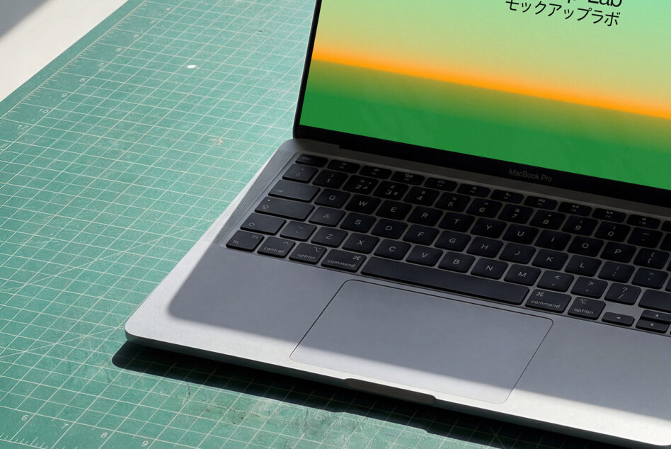 MacBook Pro on green cutting mat showing yellow orange gradient screen