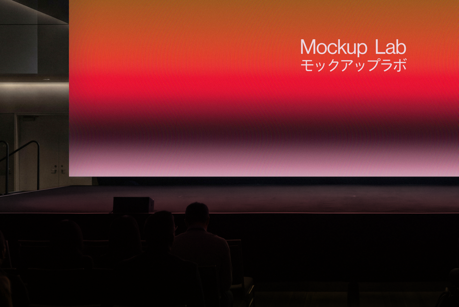 Large cinema screen displaying gradient red pink text above audience silhouettes
