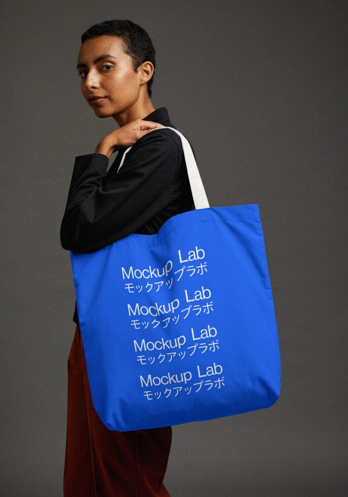 Woman wearing black jacket holding blue tote with white text