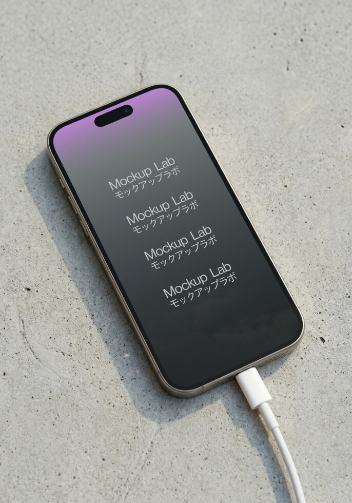 Phone charging with white cable on concrete surface, purple gradient display