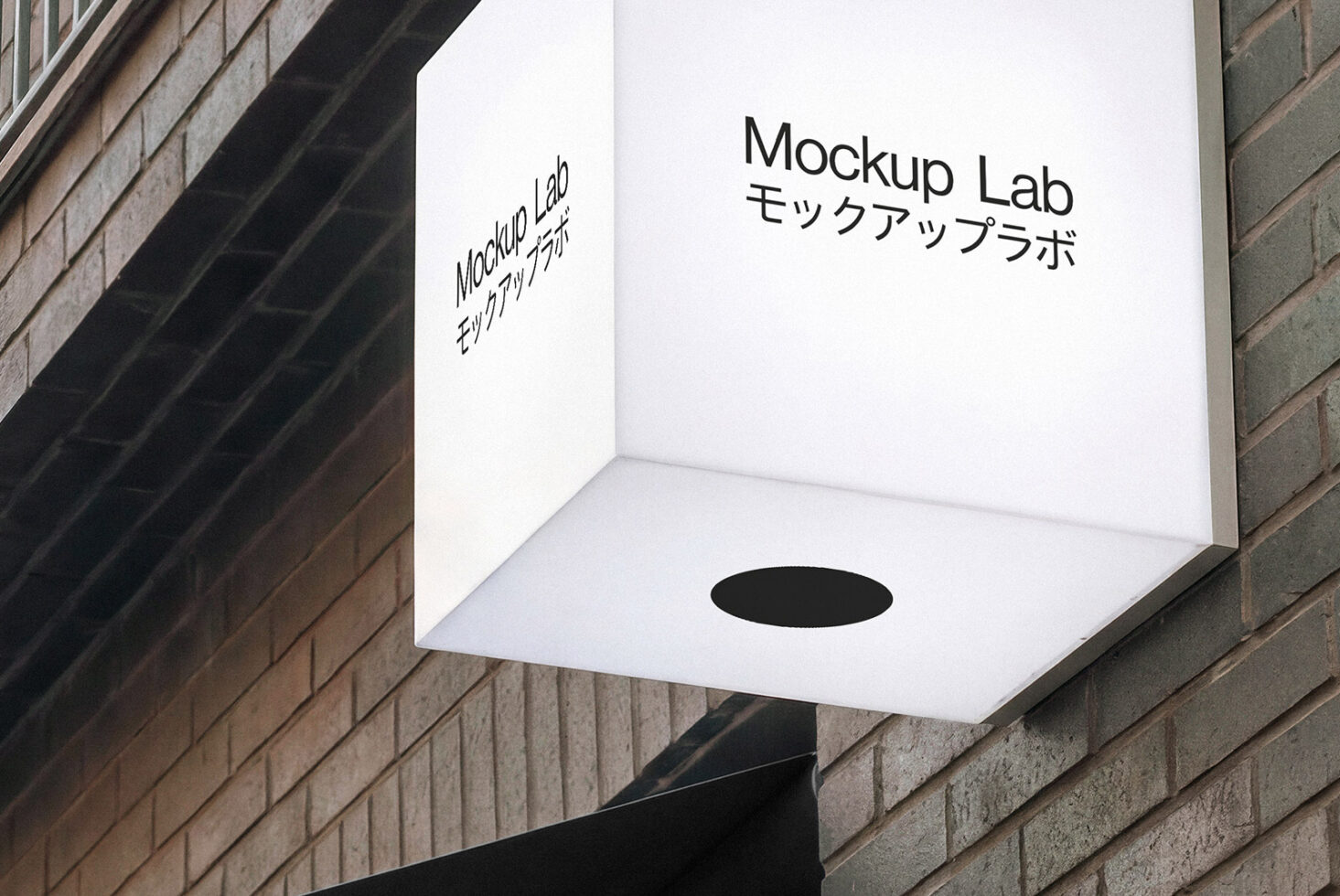 Illuminated cube storefront sign on brick wall with Mockup Lab text bilingual