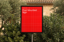 Post mounted sign with red background, white text, olive trees in background