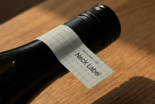 Wine bottle with light colored grid label mockup on wooden table, angled view