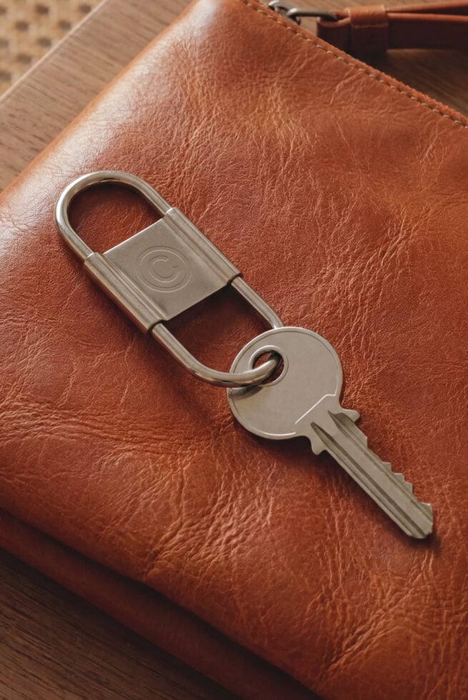 Brown leather item with metal key ring featuring circular engraved pattern