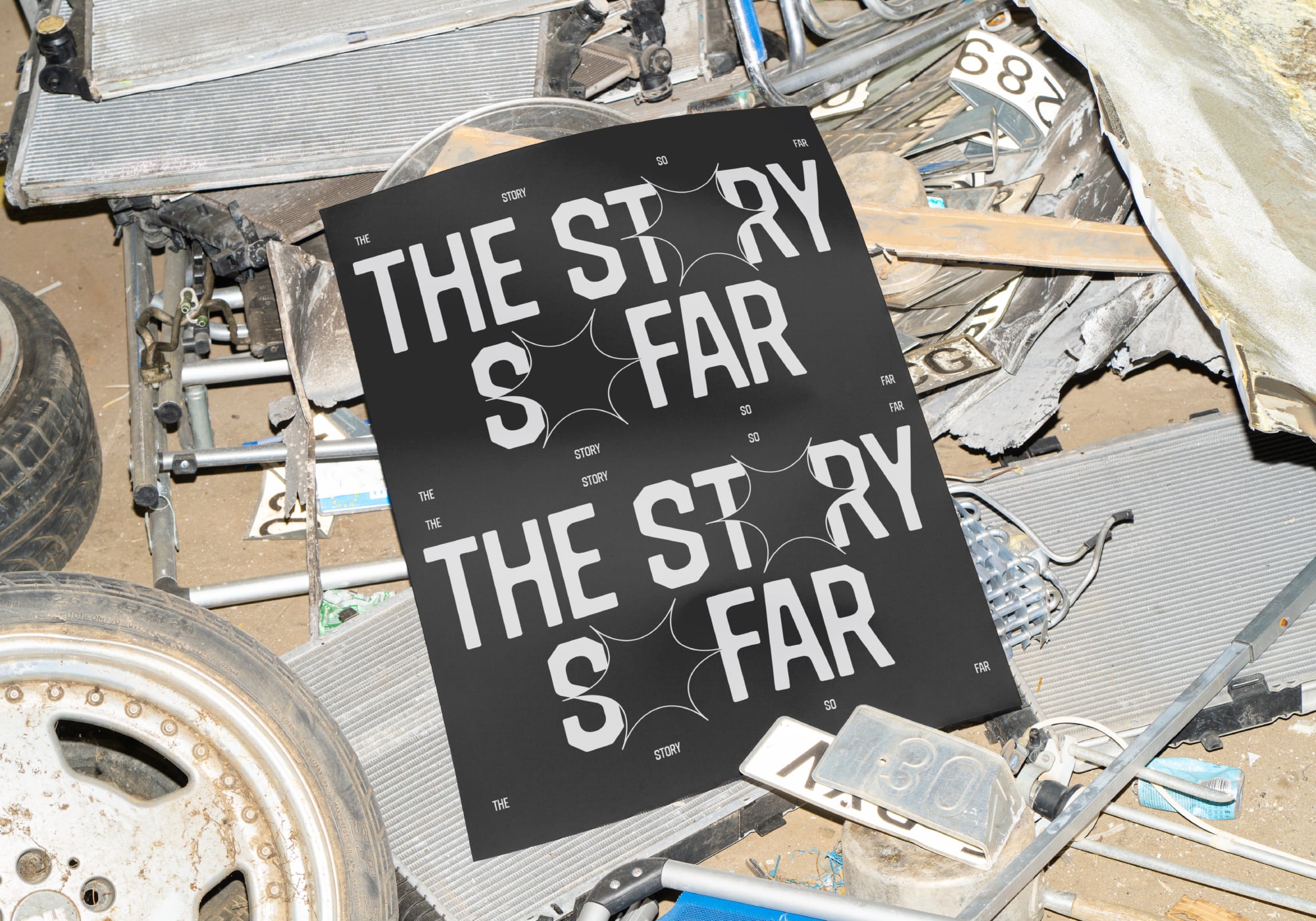 Black poster showing repeated story so far typography on industrial scrap metal background