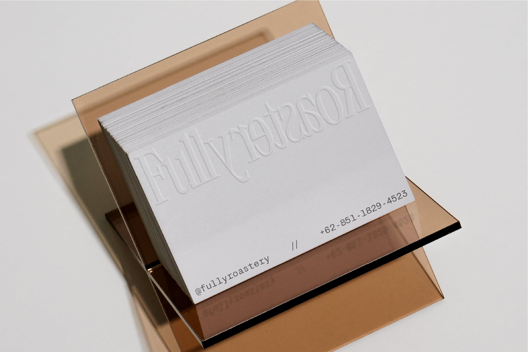 Embossed business card stack in kraft box with contact info visible