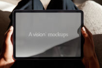 Tablet held in hands with neutral gray screen for design mockup