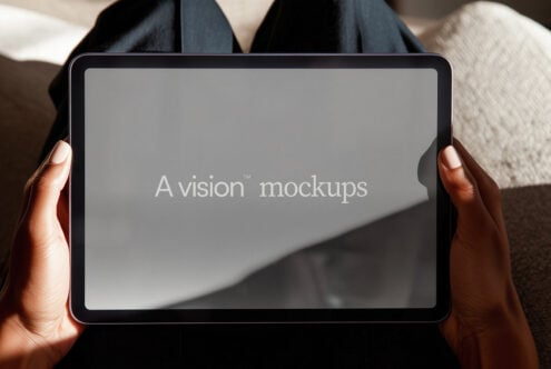 Tablet held in hands with neutral gray screen for design mockup