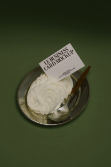 Business card mockup placed on metal dish with cream substance on green surface