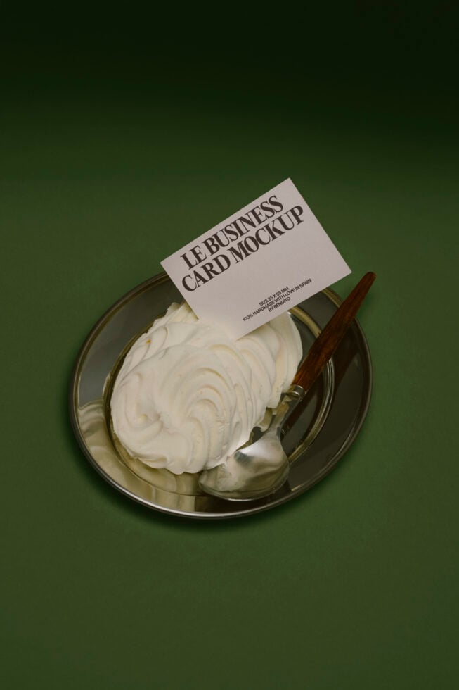 Business card mockup placed on metal dish with cream substance on green surface