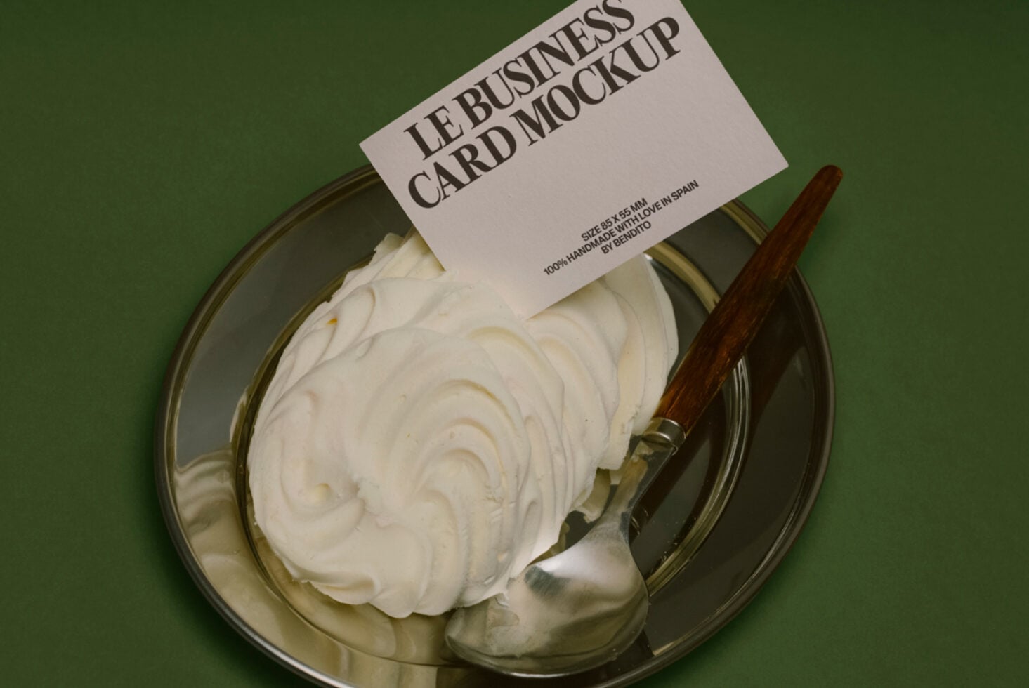 Cream spread on glass plate with wooden knife on green background