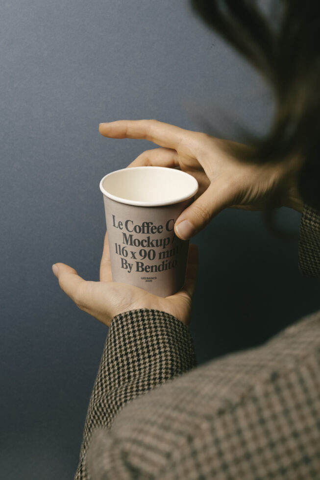 Hands holding paper coffee cup with branding text visible from top angle