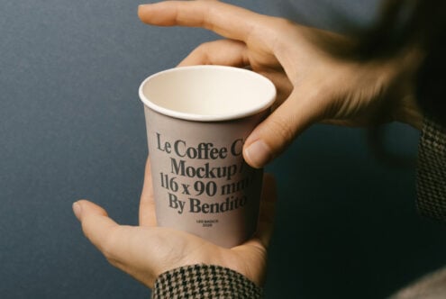 Hands cradling takeaway coffee cup with branded text label showing