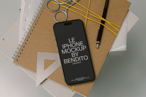 Black iPhone mockup on kraft paper with spiral notebooks, yellow string, metal rings