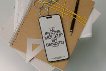 White iPhone mockup on kraft paper with spiral notebooks, yellow string, metal rings