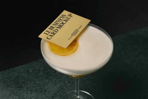 Gold business card on creamy cocktail with lemon garnish, dark backdrop