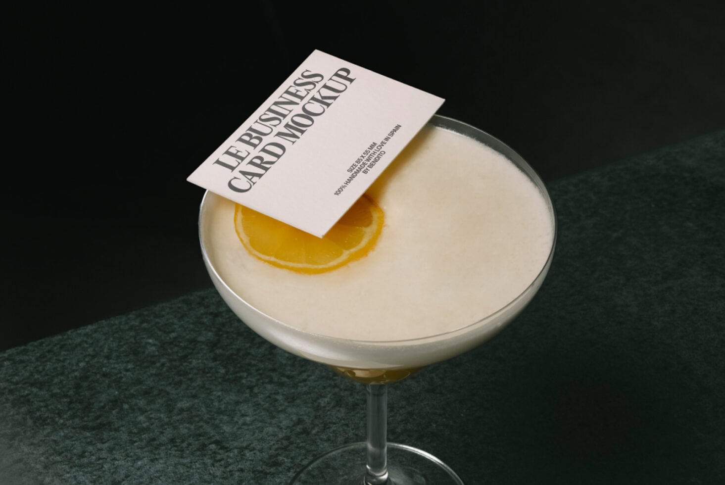 White business card on creamy cocktail with lemon garnish, dark backdrop