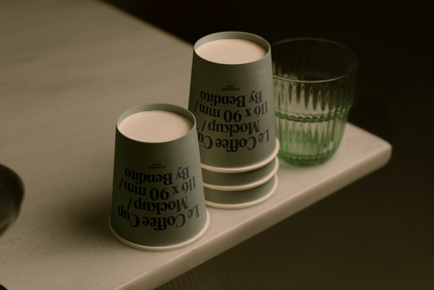 Close up of sage paper cups with reversed text print sitting on white platform