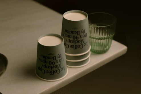 Close up of sage paper cups with reversed text print sitting on white platform