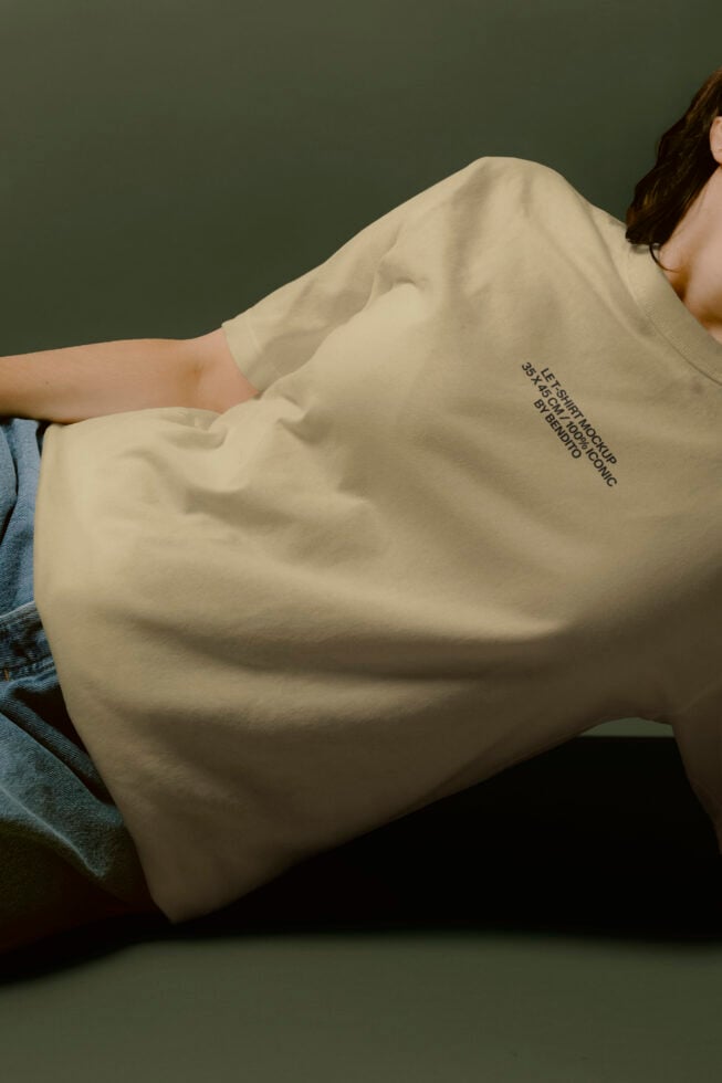 Cream oversized tee with small text print on chest, person wearing against green backdrop