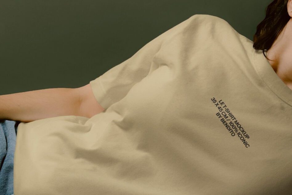 Beige crewneck tee with minimal print on torso, shot against sage green wall