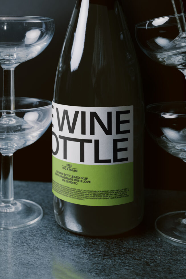 Dark wine bottle mockup with white label, surrounded by filled cocktail glasses
