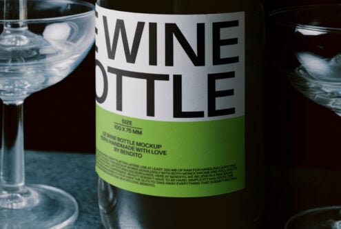 Wine bottle with white label showing green accent strip, surrounded by water glasses