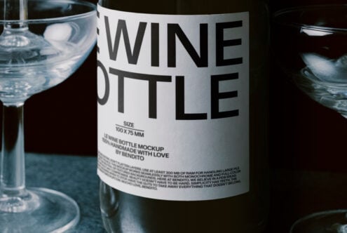 Wine bottle with white label on neutral background, sitting next to filled glasses