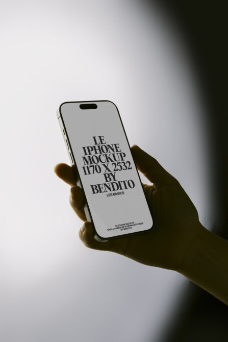 White iPhone mockup in hand with dramatic side lighting on gray
