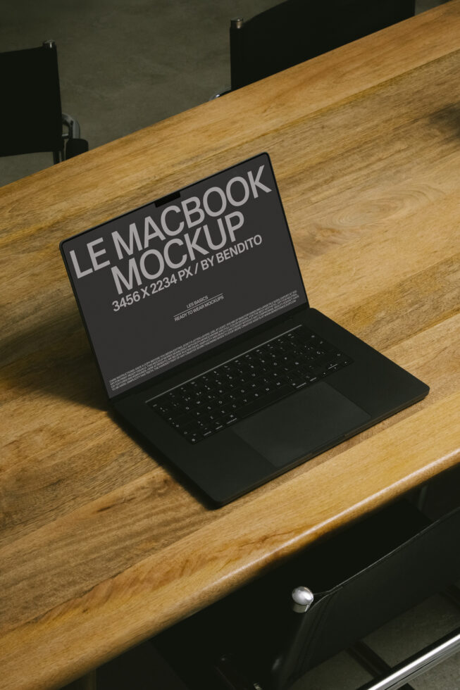 Black MacBook on wooden desk with dark gray screen displaying mockup text