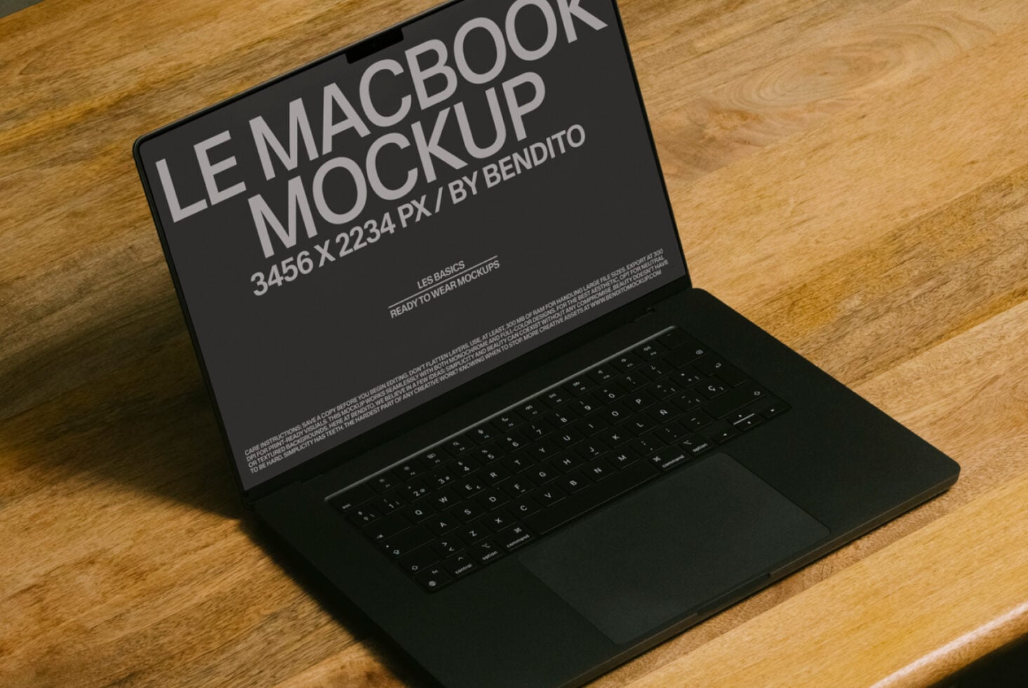 Dark MacBook sitting on wooden surface with display mockup at slight angle