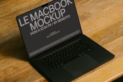 Dark MacBook sitting on wooden surface with display mockup at slight angle