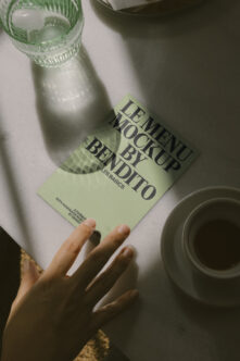 Green leaflet mockup held over water bottle, styled flatlay
