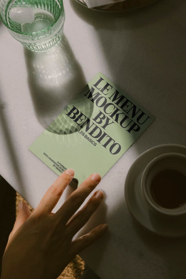 Green leaflet mockup held over water bottle, styled flatlay