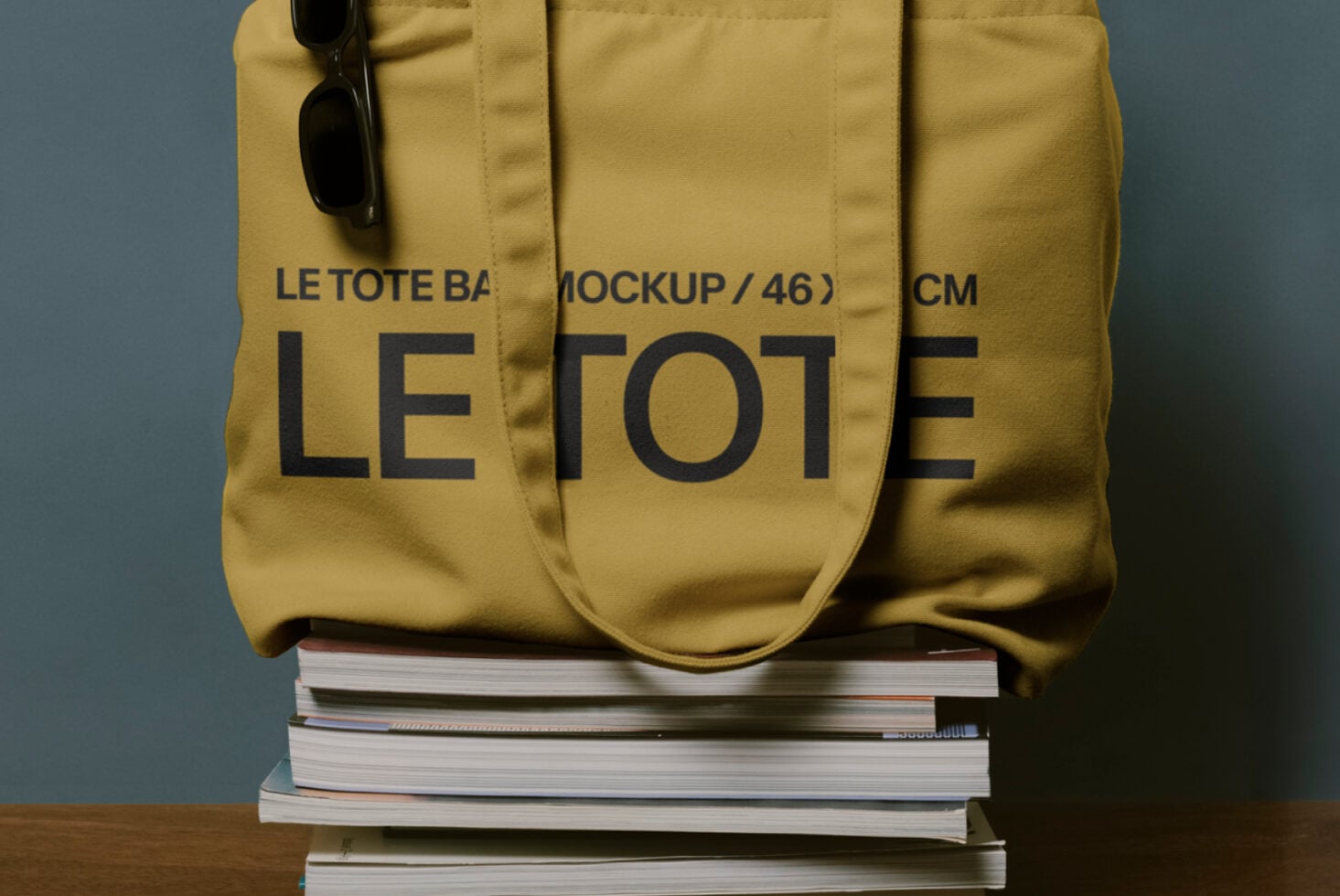 Close up of mustard yellow tote bag with Le Tote large text, dark sunglasses clipped to handle