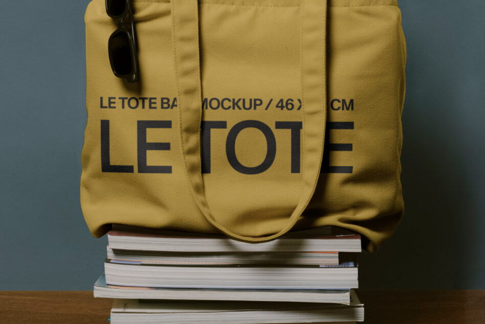 Close up of mustard yellow tote bag with Le Tote large text, dark sunglasses clipped to handle