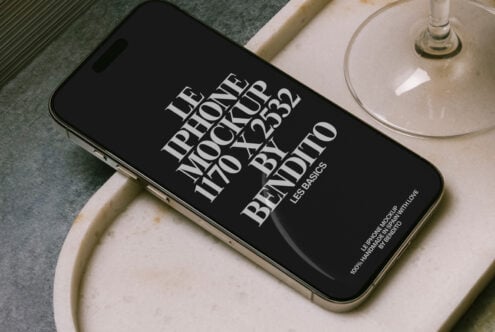 Black iPhone landscape on cream ceramic dish next to cocktail glass overhead shot