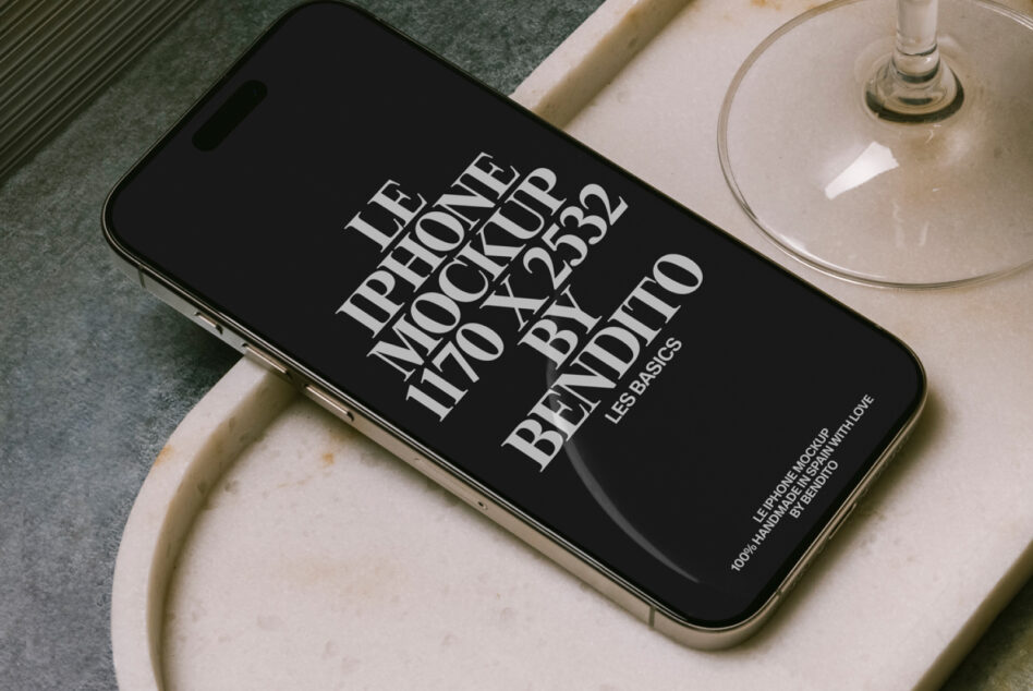 Black iPhone landscape on cream ceramic dish next to cocktail glass overhead shot