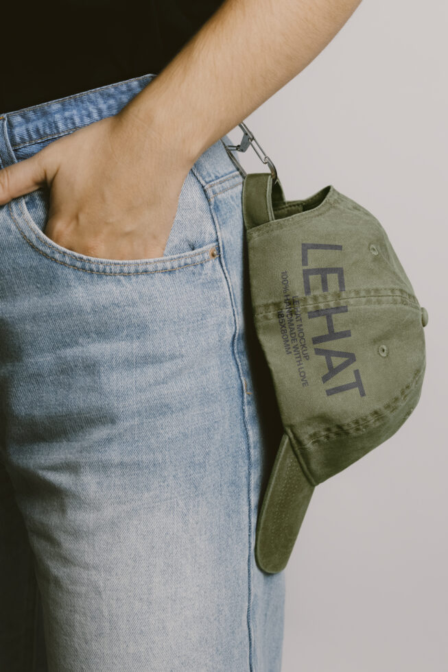 Person wearing light denim holding olive canvas tote with Les Hat logo