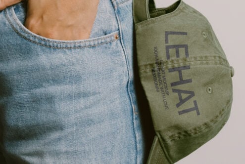 Close up of light denim with olive canvas tote bag featuring Les Hat text