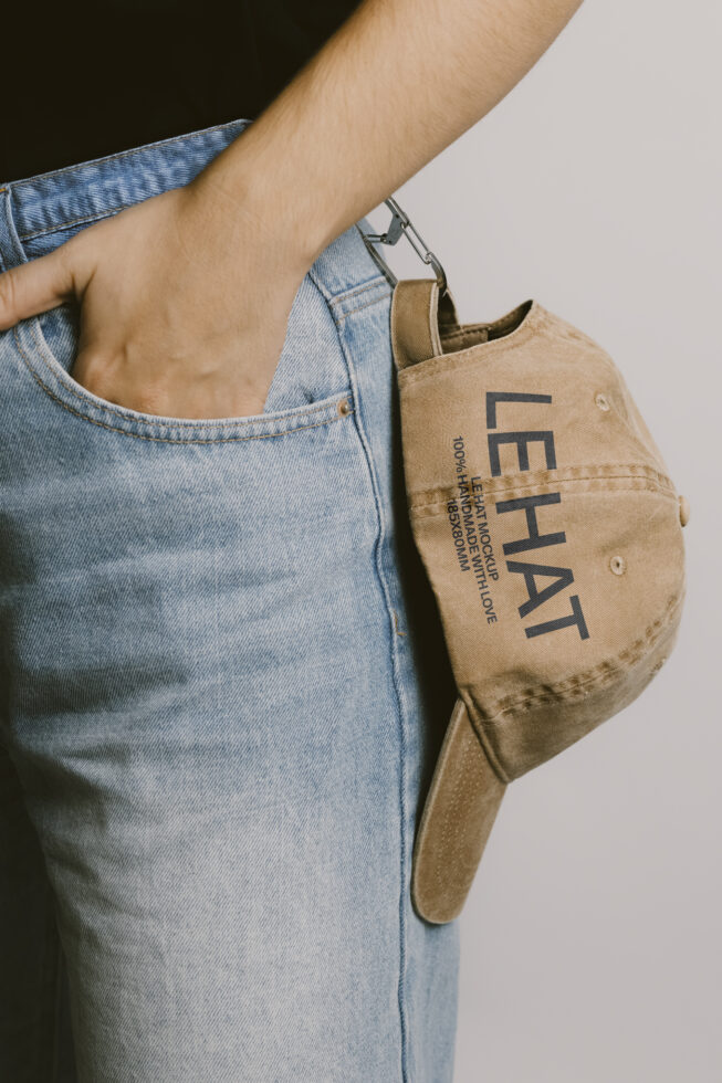 Person in light denim holding beige canvas tote with Les Hat branding