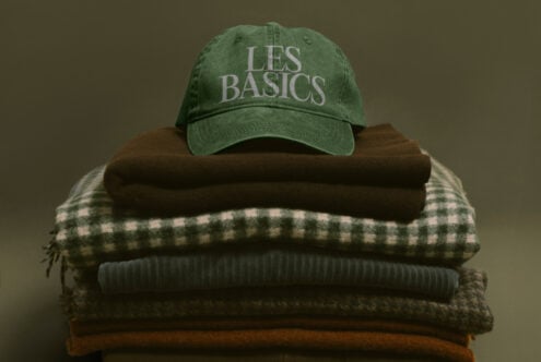 Green vintage cap with Les Basics text stacked on folded sweaters