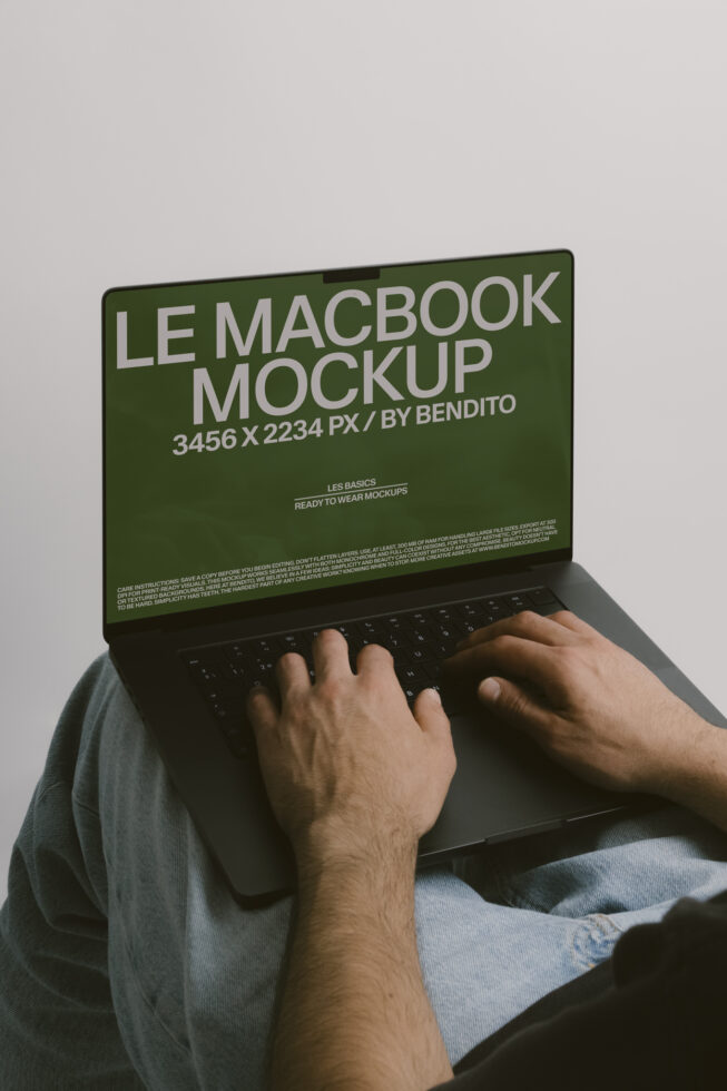 Hands typing on MacBook with green screen displaying white sans serif text